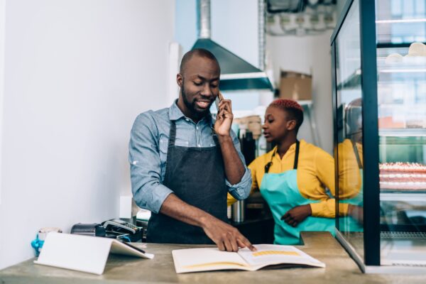 African,American,Male,In,Apron,Checking,Information,In,Open,Notepad