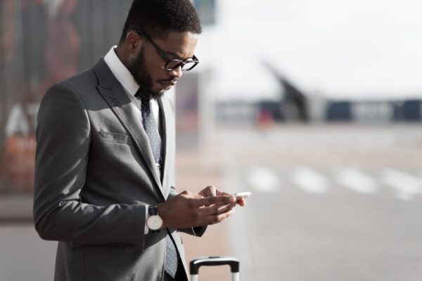 Ordering,Taxi.,Afro,Businessman,Using,Mobile,Phone,App,,Arriving,At