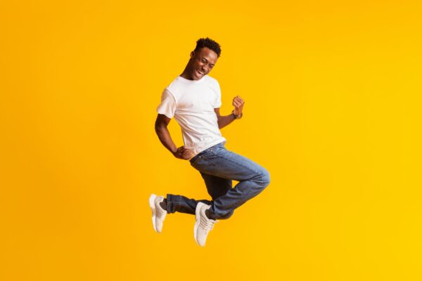 Successful,Moment.,Happy,Excited,Young,Black,Man,Jumping,Over,Yellow